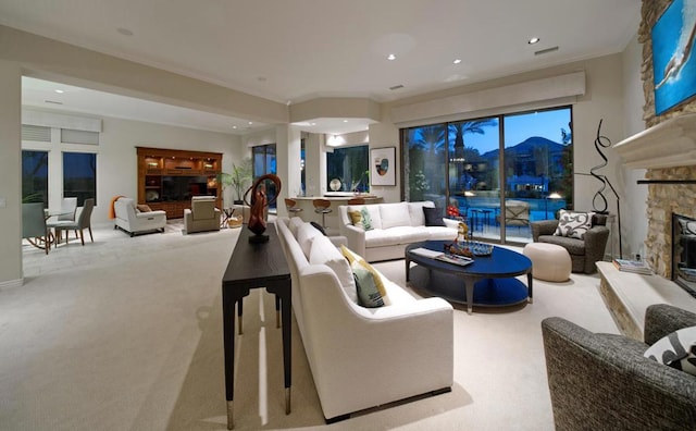 carpeted living room featuring a stone fireplace and crown molding