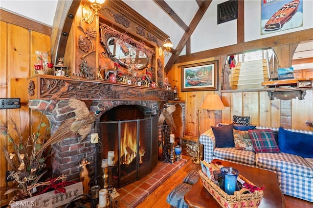 living room with hardwood / wood-style floors, a large fireplace, wood walls, and high vaulted ceiling