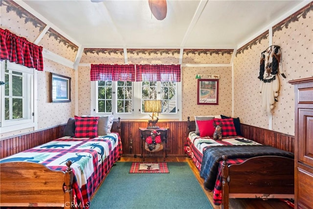 bedroom with ceiling fan, hardwood / wood-style floors, and wood walls