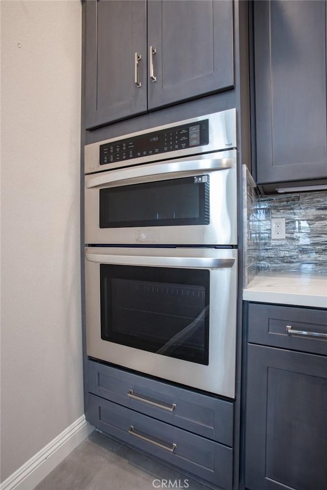 kitchen with stainless steel double oven and tasteful backsplash