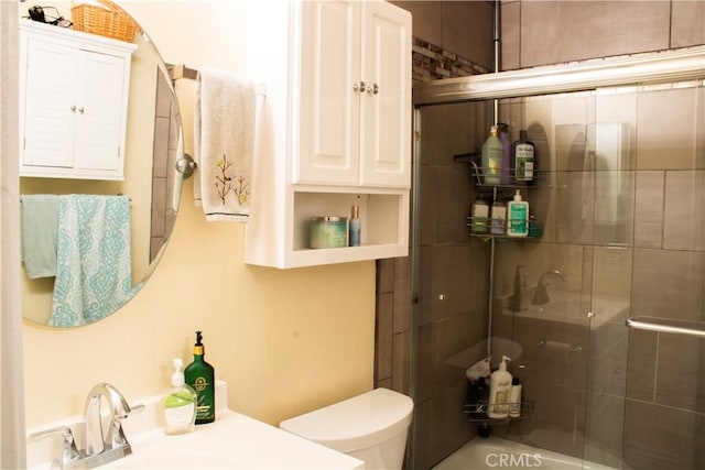 bathroom featuring toilet, an enclosed shower, and sink