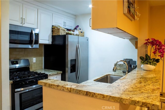 kitchen featuring white cabinetry, sink, kitchen peninsula, decorative backsplash, and appliances with stainless steel finishes