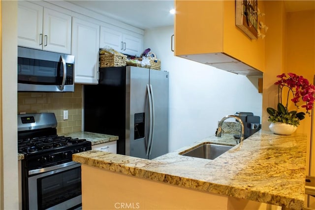 18645 Hatteras St Unit 186, Tarzana, CA 91356 - kitchen with appliances with stainless steel finishes, tasteful backsplash, white cabinets, light stone countertops, and a peninsula