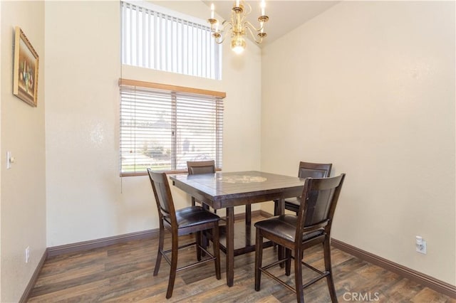 dining area with dark hardwood / wood-style flooring, lofted ceiling, and an inviting chandelier