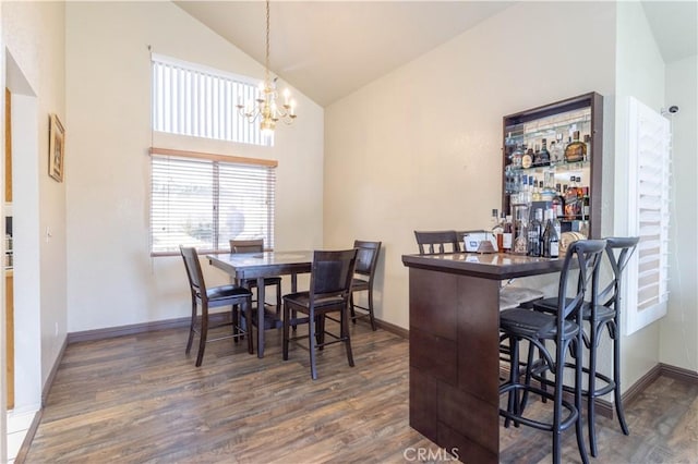 dining area featuring dark hardwood / wood-style flooring, high vaulted ceiling, and an inviting chandelier