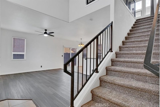 stairs with ceiling fan with notable chandelier and hardwood / wood-style flooring