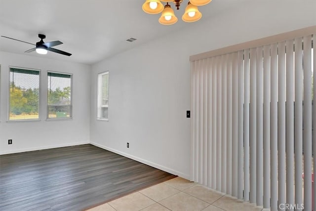 spare room featuring light hardwood / wood-style floors and ceiling fan with notable chandelier