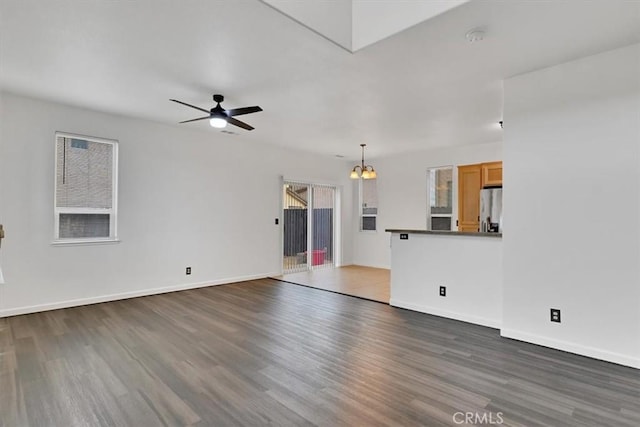 unfurnished living room featuring dark wood-type flooring and ceiling fan with notable chandelier