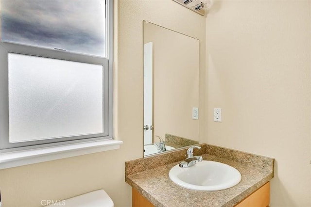 bathroom with vanity, toilet, and a healthy amount of sunlight