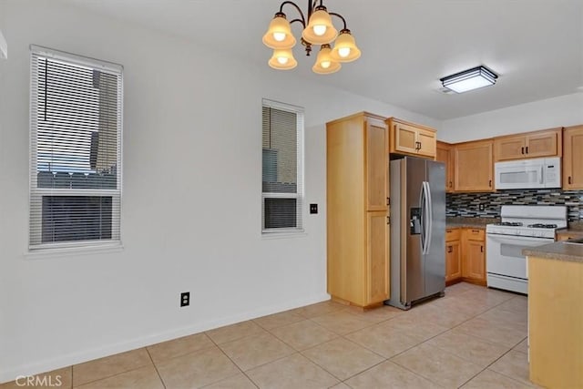 kitchen featuring white appliances, hanging light fixtures, decorative backsplash, light tile patterned floors, and a notable chandelier