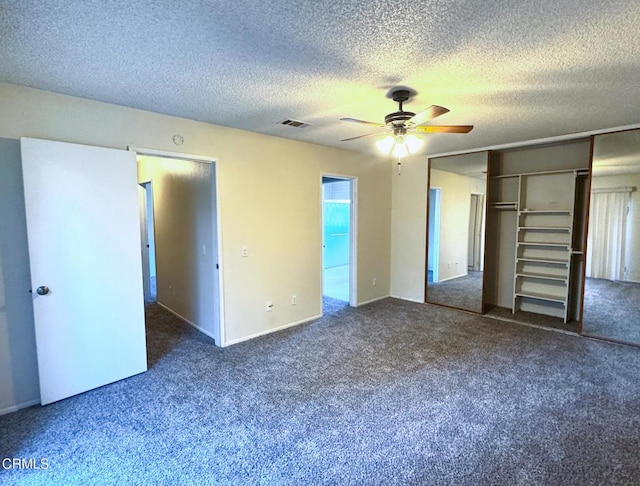 unfurnished bedroom featuring dark colored carpet, a textured ceiling, a closet, and ceiling fan