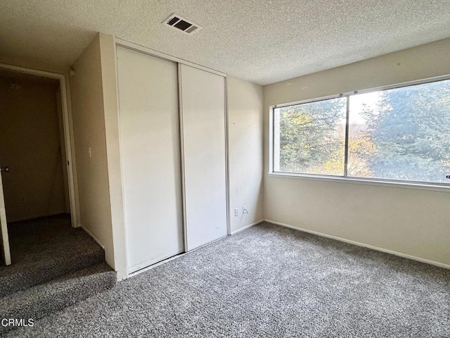 unfurnished bedroom with carpet flooring, a textured ceiling, and a closet