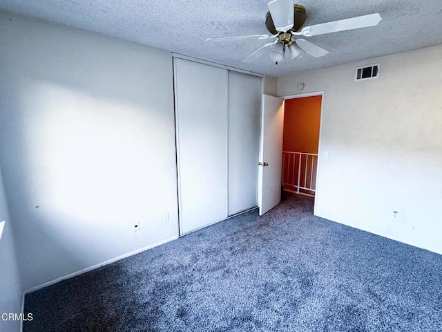 unfurnished bedroom with carpet, ceiling fan, a textured ceiling, and a closet