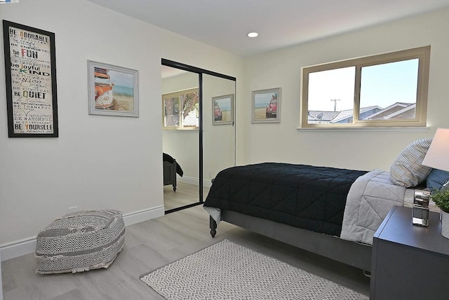 bedroom with light hardwood / wood-style floors and a closet