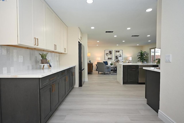 kitchen with white cabinetry, dishwasher, black refrigerator, kitchen peninsula, and backsplash