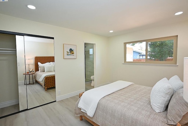 bedroom with light wood-type flooring and ensuite bathroom