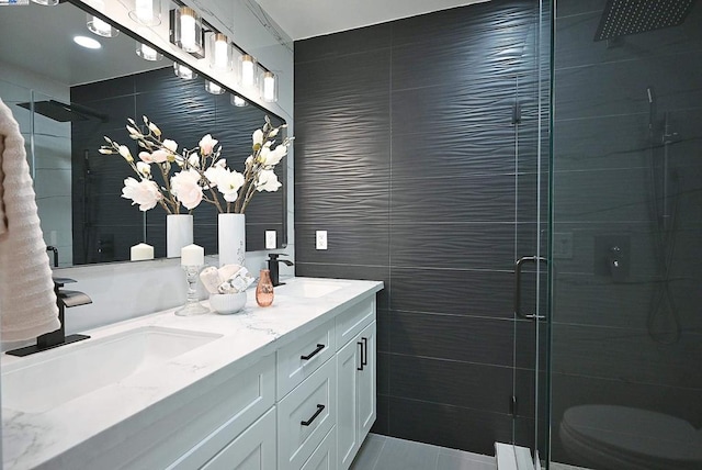 bathroom with toilet, an enclosed shower, vanity, and tile walls