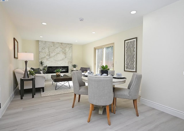 dining room featuring a premium fireplace and light wood-type flooring