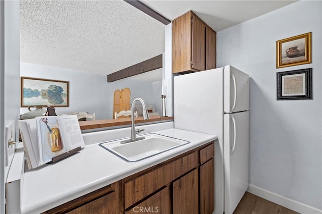 kitchen featuring dark hardwood / wood-style floors, sink, white fridge, and a textured ceiling