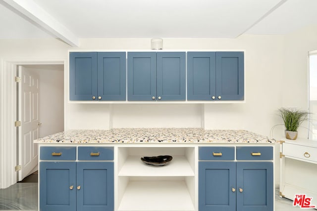 kitchen featuring light stone counters and blue cabinetry