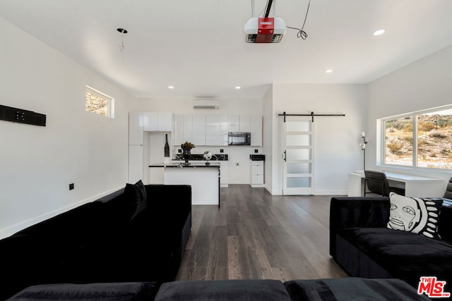 living room with a barn door, dark wood-type flooring, and a wall mounted AC