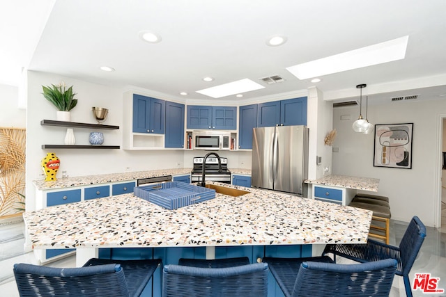 kitchen featuring appliances with stainless steel finishes, a skylight, blue cabinetry, hanging light fixtures, and a breakfast bar area