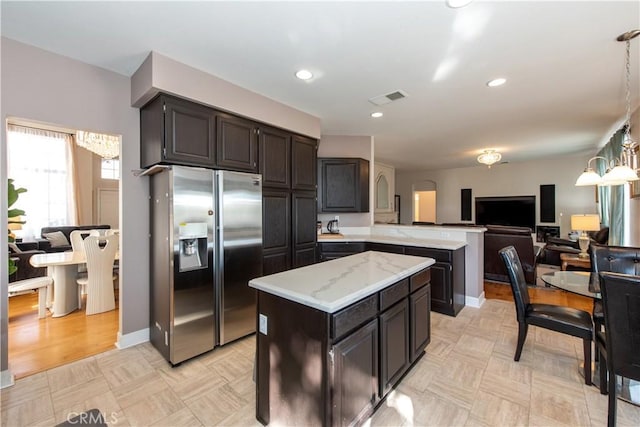 kitchen with pendant lighting, light hardwood / wood-style flooring, stainless steel fridge, a kitchen island, and kitchen peninsula