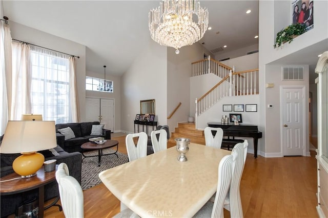 dining space with high vaulted ceiling, light hardwood / wood-style floors, and a notable chandelier