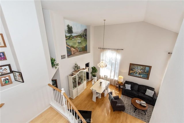 living room with high vaulted ceiling, hardwood / wood-style flooring, and an inviting chandelier