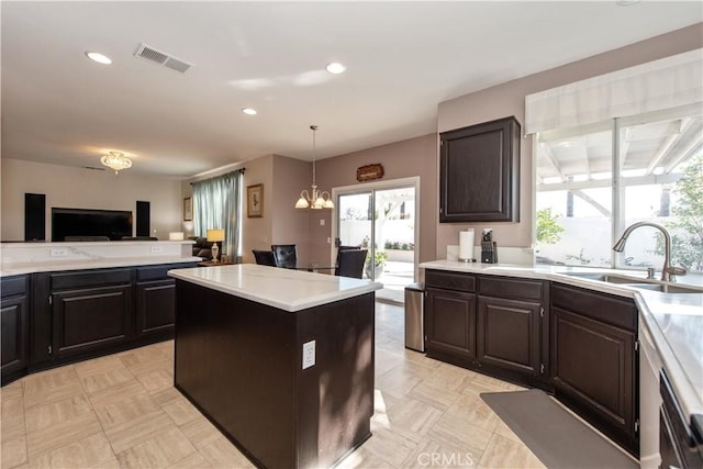 kitchen with pendant lighting, a center island, sink, dark brown cabinets, and a chandelier