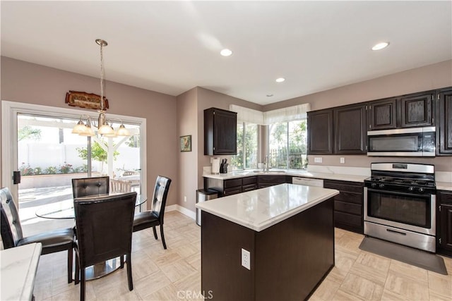 kitchen with sink, hanging light fixtures, a notable chandelier, a kitchen island, and stainless steel appliances