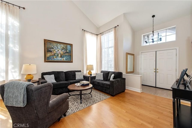 living room featuring a chandelier, hardwood / wood-style floors, high vaulted ceiling, and a healthy amount of sunlight