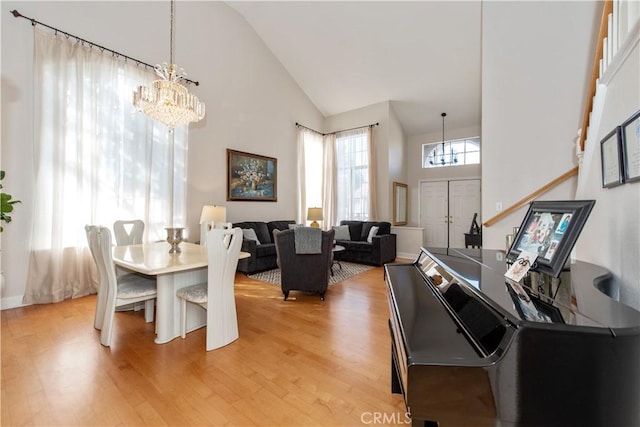 dining room featuring light hardwood / wood-style flooring, high vaulted ceiling, and a chandelier