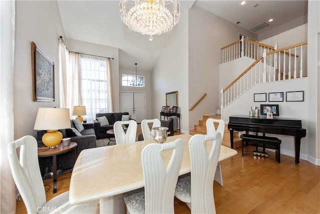 dining room featuring high vaulted ceiling, light hardwood / wood-style flooring, and a notable chandelier