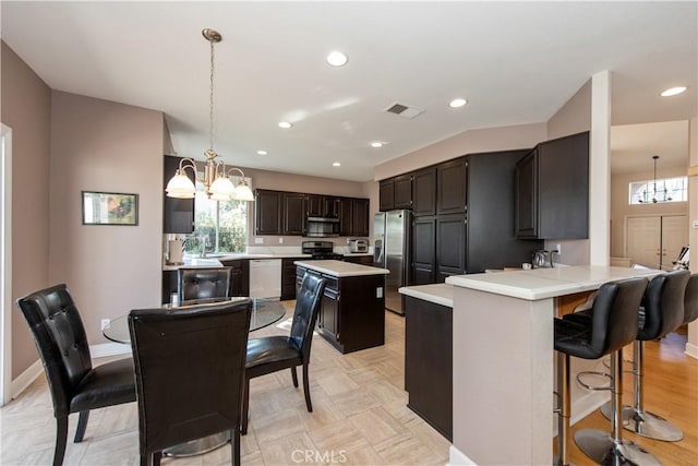 kitchen featuring kitchen peninsula, dark brown cabinetry, stainless steel appliances, decorative light fixtures, and a center island