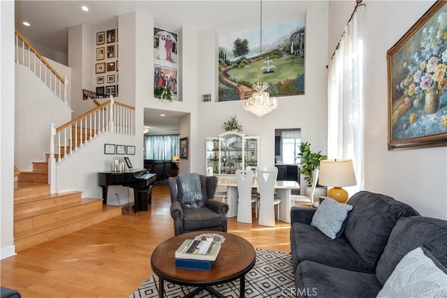 living room with a towering ceiling, light hardwood / wood-style floors, and an inviting chandelier