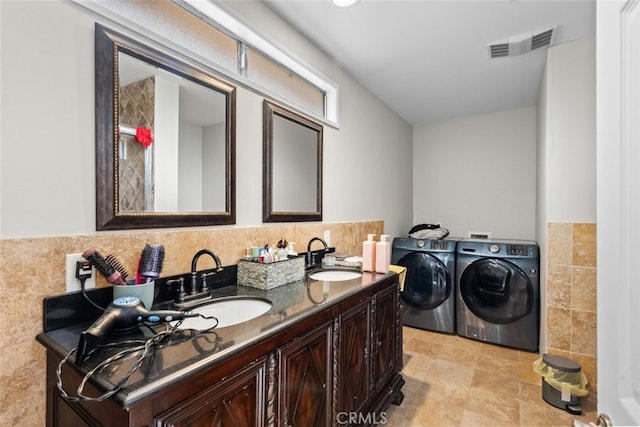 bathroom featuring washer and dryer, vanity, and tile walls