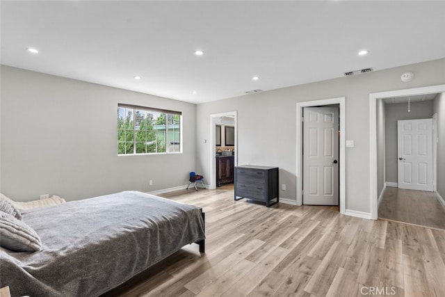 bedroom featuring ensuite bathroom and light hardwood / wood-style floors