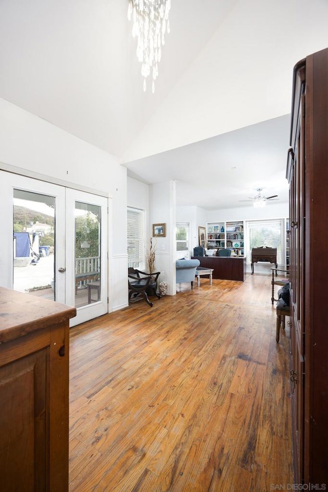 interior space featuring a healthy amount of sunlight, french doors, ceiling fan with notable chandelier, and light hardwood / wood-style floors