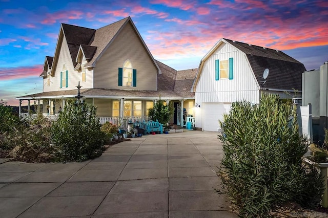 back house at dusk featuring a garage and a porch