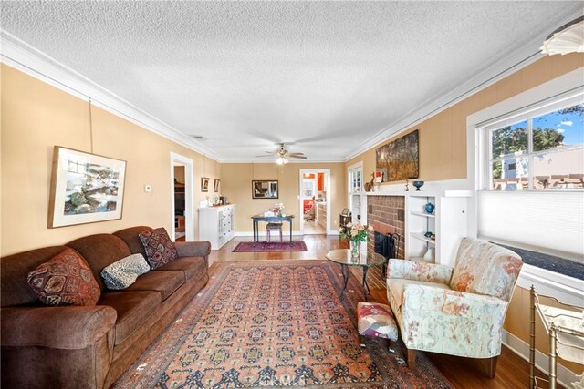 living room with a fireplace, a textured ceiling, ceiling fan, and ornamental molding