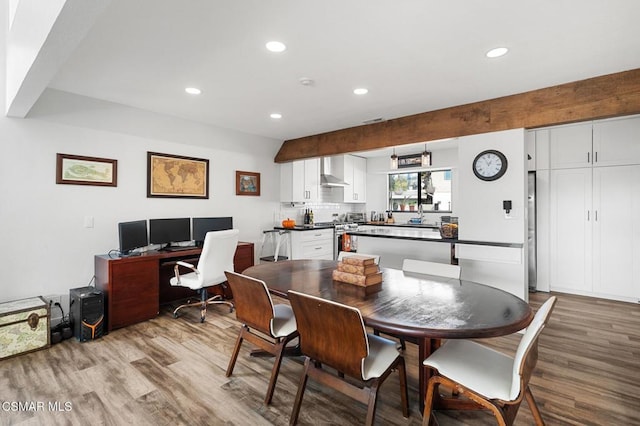 dining room featuring beamed ceiling and light wood-type flooring