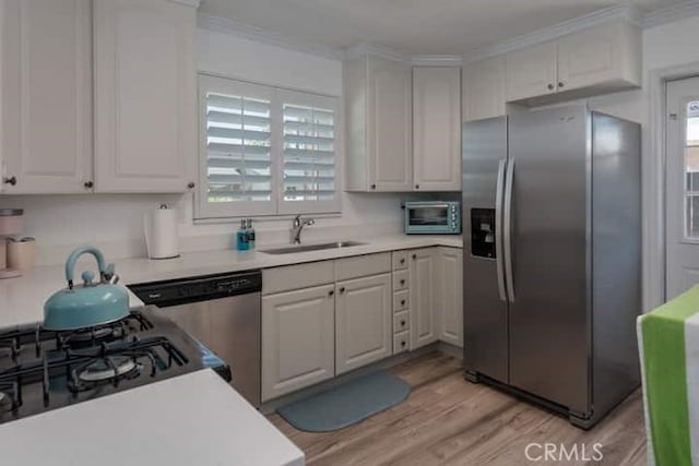 kitchen featuring sink, stainless steel appliances, light hardwood / wood-style floors, white cabinets, and ornamental molding