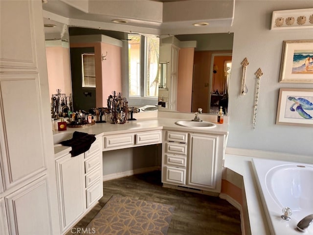 bathroom with hardwood / wood-style floors, vanity, and a tub