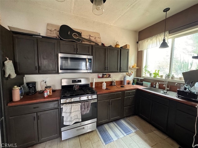 kitchen with wooden counters, dark brown cabinets, stainless steel appliances, and sink