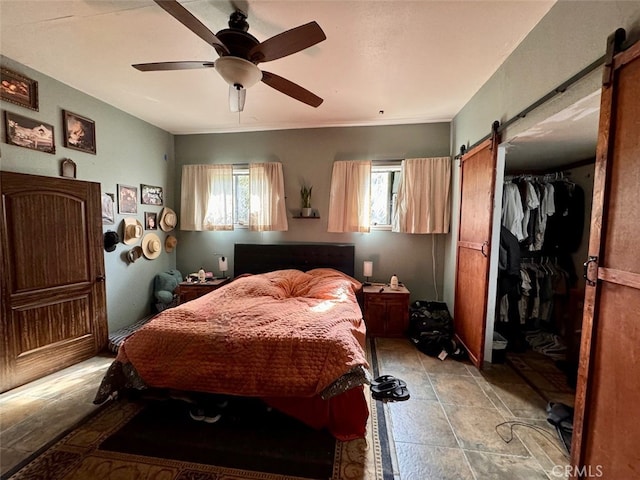 bedroom with ceiling fan, a barn door, and a closet