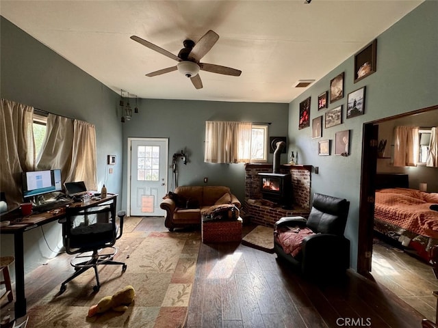 office area with hardwood / wood-style flooring, ceiling fan, and a wood stove