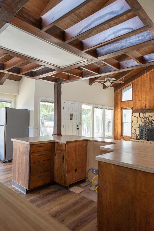 kitchen with wooden ceiling, vaulted ceiling with beams, dark hardwood / wood-style flooring, kitchen peninsula, and stainless steel refrigerator