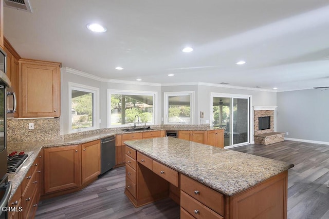 kitchen featuring sink, a center island, a stone fireplace, and dark wood-type flooring