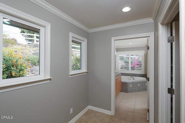 corridor featuring light tile patterned floors, crown molding, and a healthy amount of sunlight